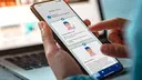 A person is holging a smartphone.You see a screenshot from the app Thieme TeleCoach.