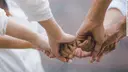 Close-up of several hands clenched into fists and brought together in the middle