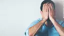 Desperate man sits on the floor with his hands covering his face