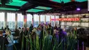 Menschen im Innenraum der rBB Dachlounge mit Glasfront und Barbereich