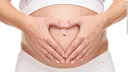 Pregnant woman who has her hands in front of her belly formed as a heart 