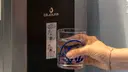 Hand hält ein Glas vor einem Wasserspender.