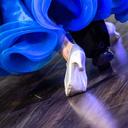 The legs of a dancing couple with the hem of a blue ball gown
