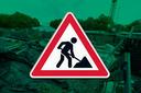 Im Hintergrund eine Baustelle, im Vordergrund ein "Achtung, Baustelle"-Schild