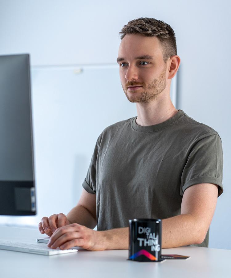 Alex an einem Stehtisch vor dem Computer