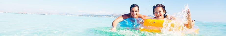 Pärchen auf Luftmatratzen im Meer.