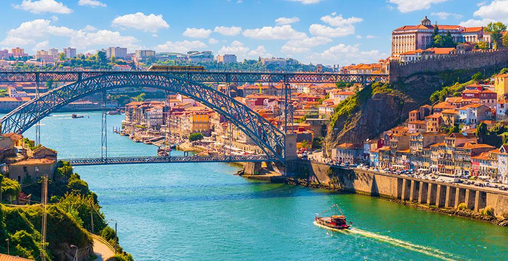 Aussicht auf die farbenfrohe Altstadt von Porto in Portugal mit der Brücke Ponte Dom Luis über den Fluss Douro.