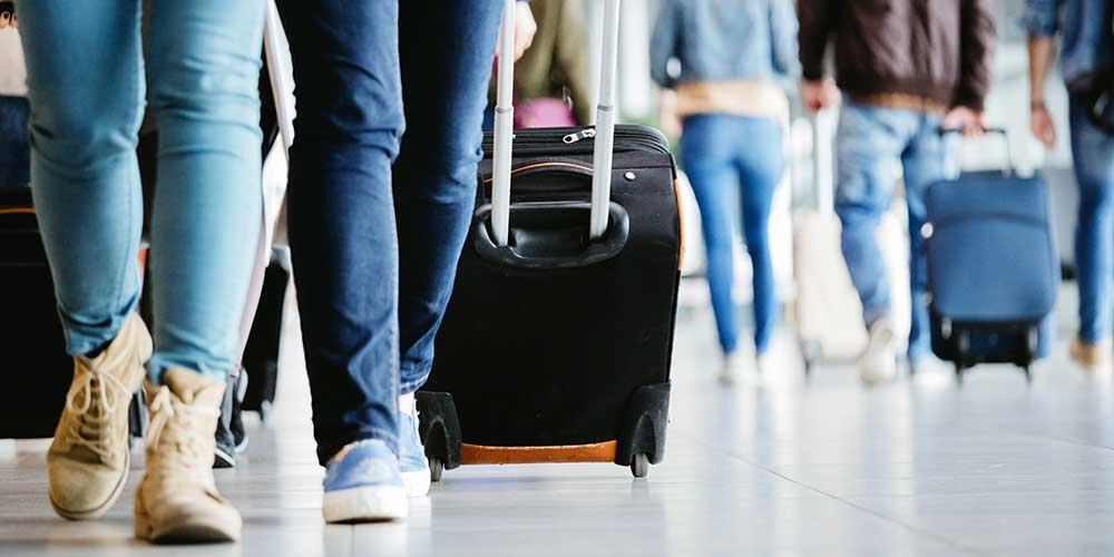 Passagiere mit Rollkoffern am Flughafen.