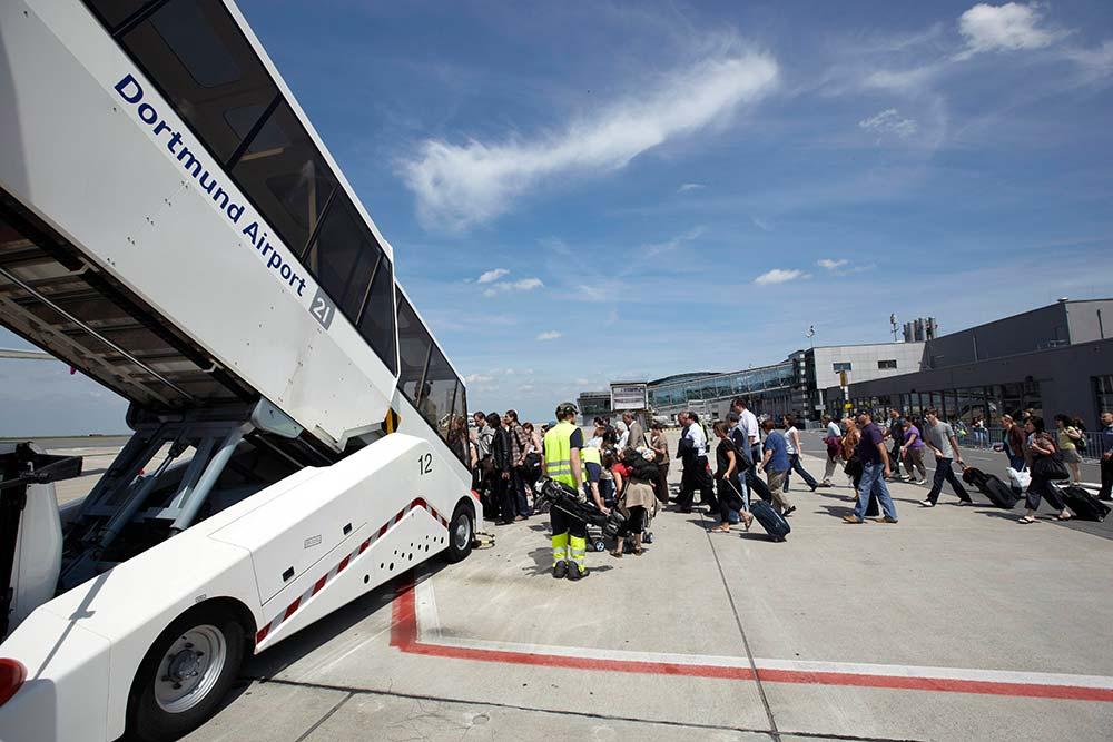 Passagiere steigen am Dortmund Airport über eine Fluggasttreppe in ein Flugzeug ein.