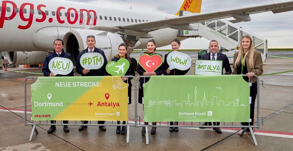 Die Crew des Pegasus Erstflugs nach Antalya und die Pressesprecherin des Dortmunder Flughafens, Carolin Rathmann, stehen auf dem Vorfeld vor der Maschine.