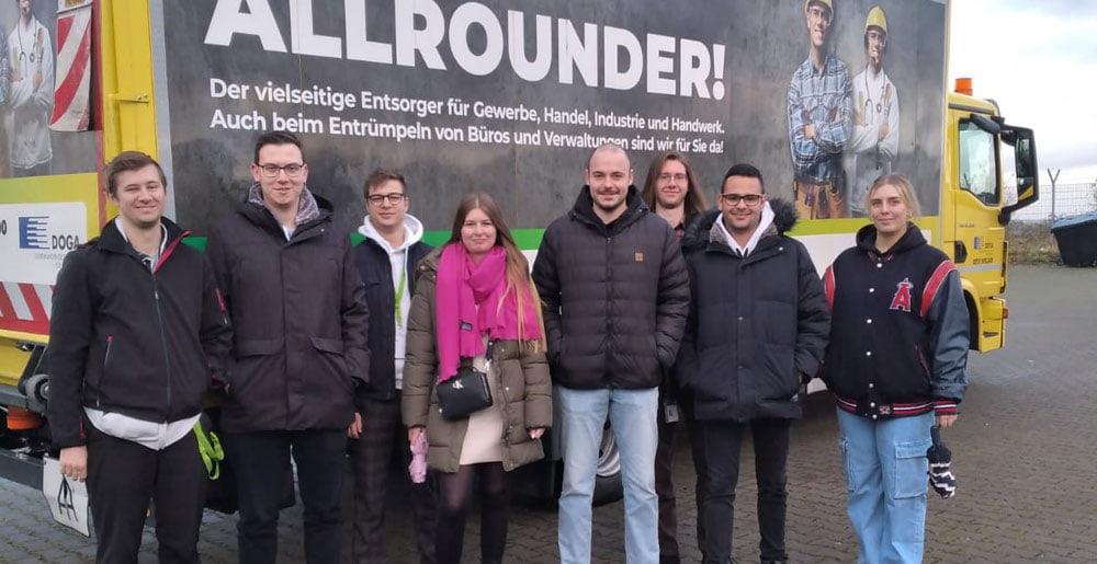 Die Auszubildenden des Dortmunder Flughafens stehen beim Nachhaltigkeitsworkshop 2023 vpor einem Truck der Abfallentsorgung