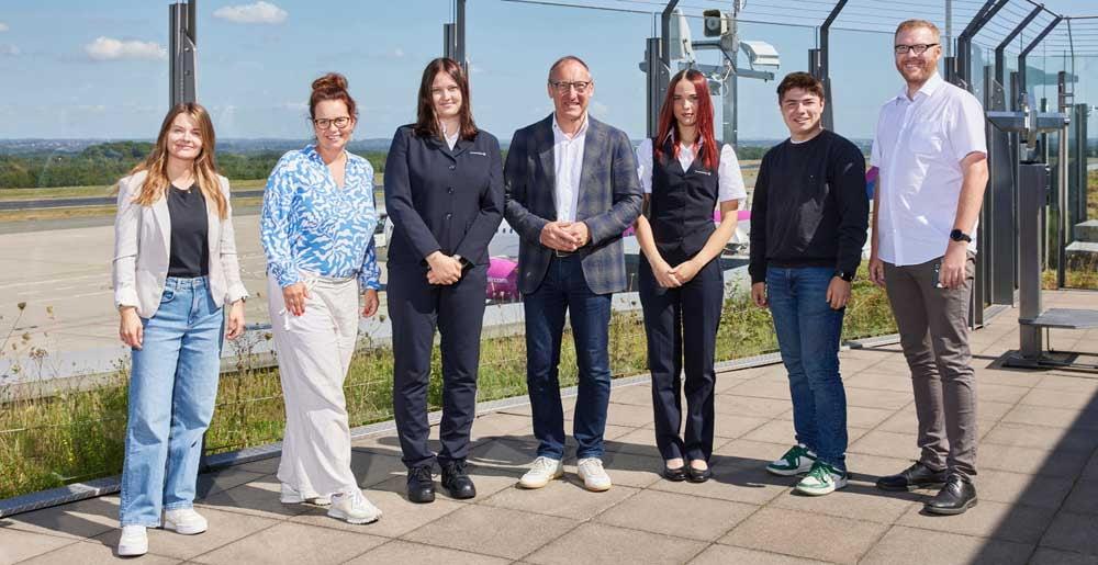 Die drei neuen Auszubildenden des Dortmunder Flughafens werden auf der Besucherterasse von Geschäftsführer Ludger van Bebber, den Ausbildungskoordinatorinnen und dem Betriebstratsvorsitzenden begrüßt.