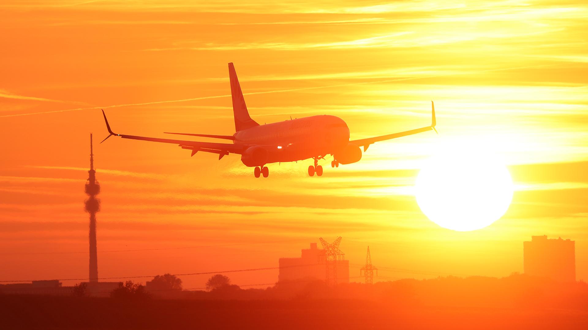 Landendes Flugzeug vor Dortmunds Skyline bei Sonnenuntergang