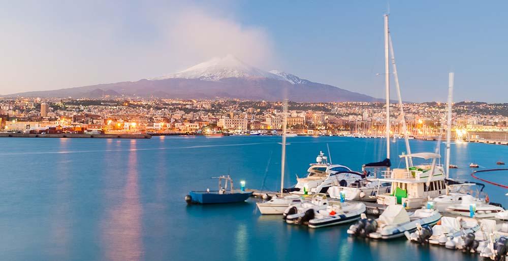 Skyline und Hafen von Catania auf Sizilien mit dem Vulkan Ätna im Hintergrund.