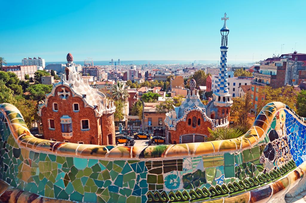A mosaic terrace overlooking colorful buildings and the Barcelona skyline.