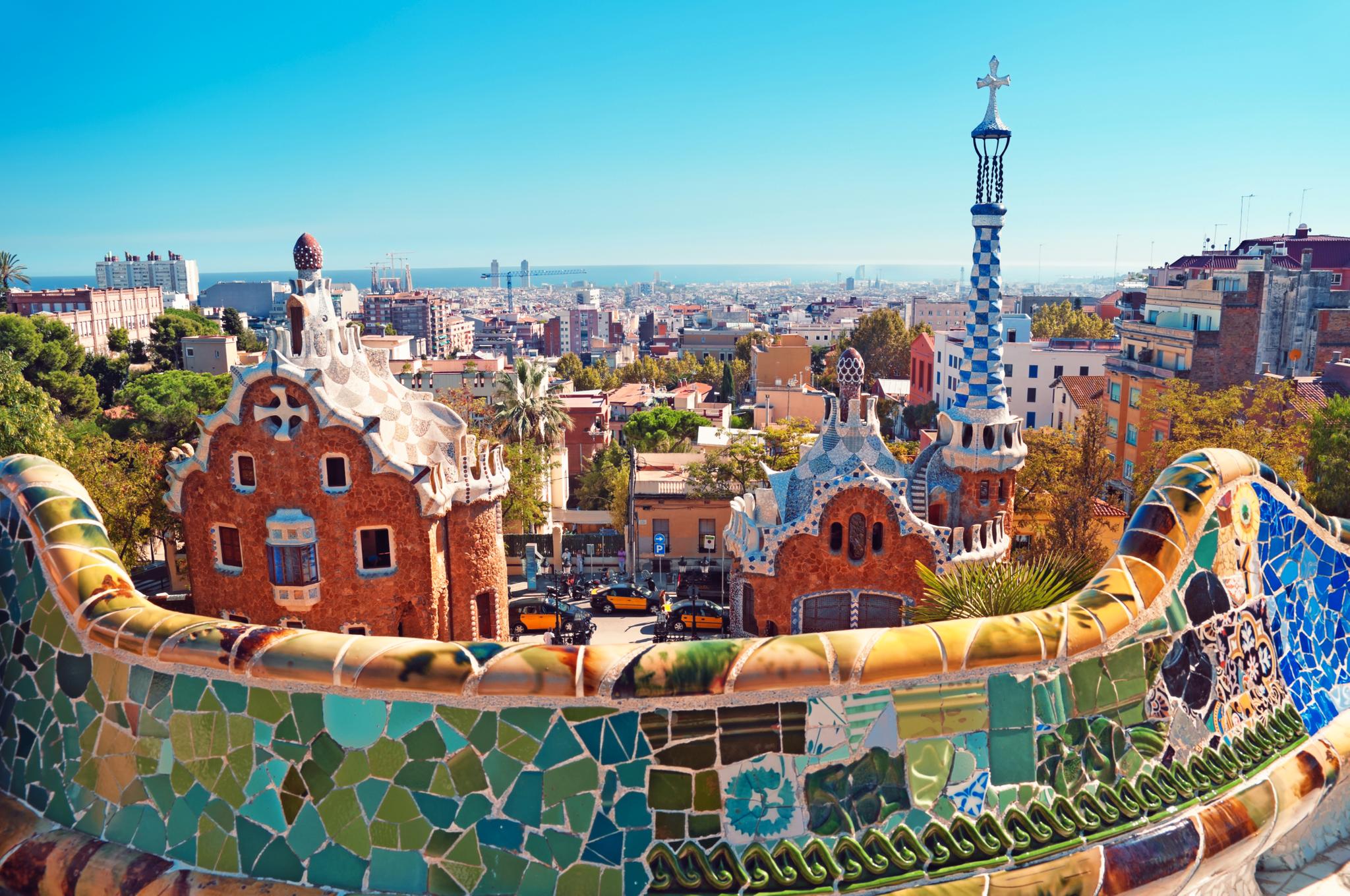 A mosaic terrace overlooking colorful buildings and the Barcelona skyline.