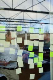 Menschen stehen hinter einem Fenster, auf dem Post Its kleben