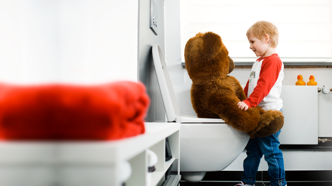 Kind mit Bär auf Toilette