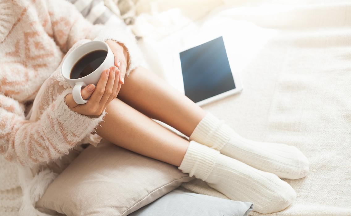 Frau entspannt mit Kaffee auf dem Sofa