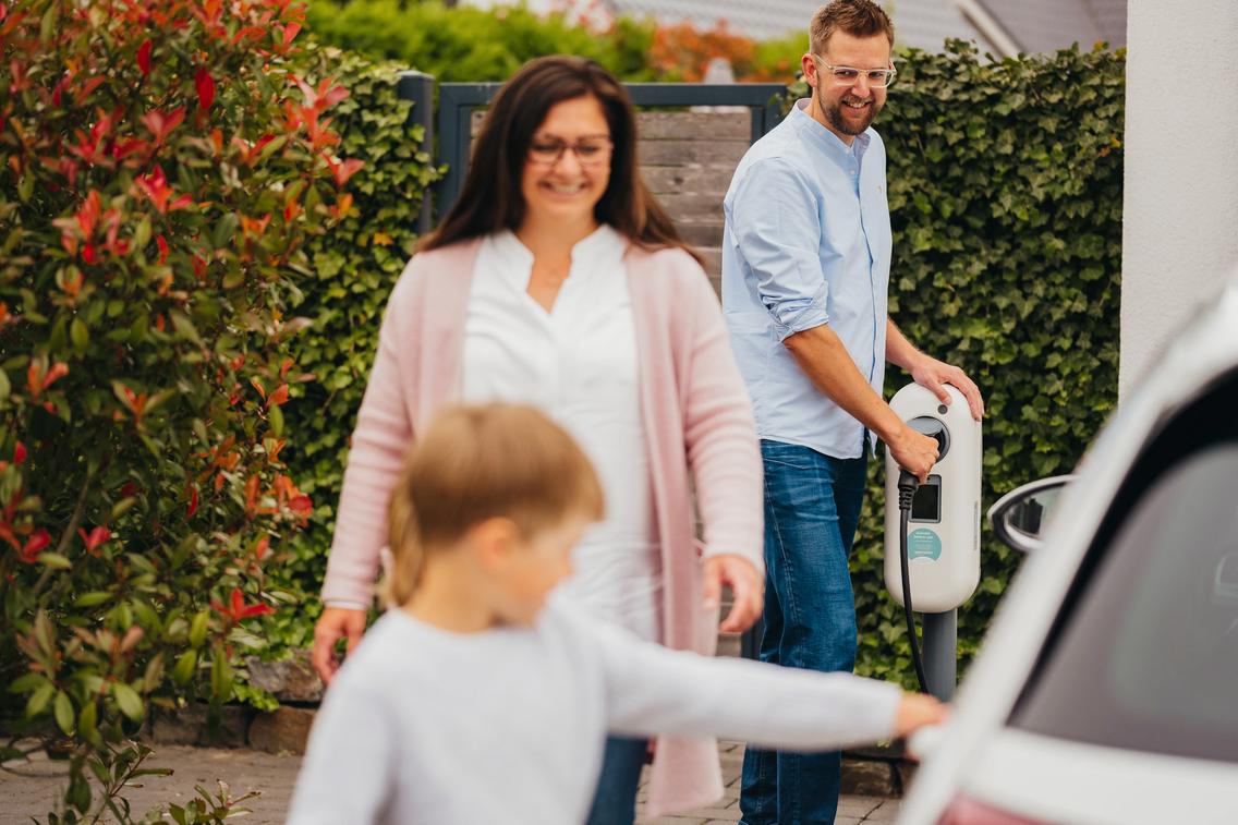 Familie lädt Ihr E-Auto an einer Ladebox Zuhause