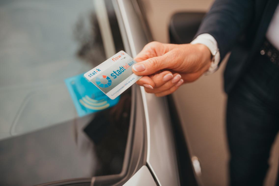 Frau öffnet mit eier Kundenkarte Carsharing-Auto