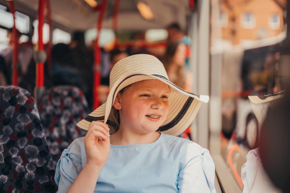 Schülerin mit Hut fährt mit Sommerferienticket