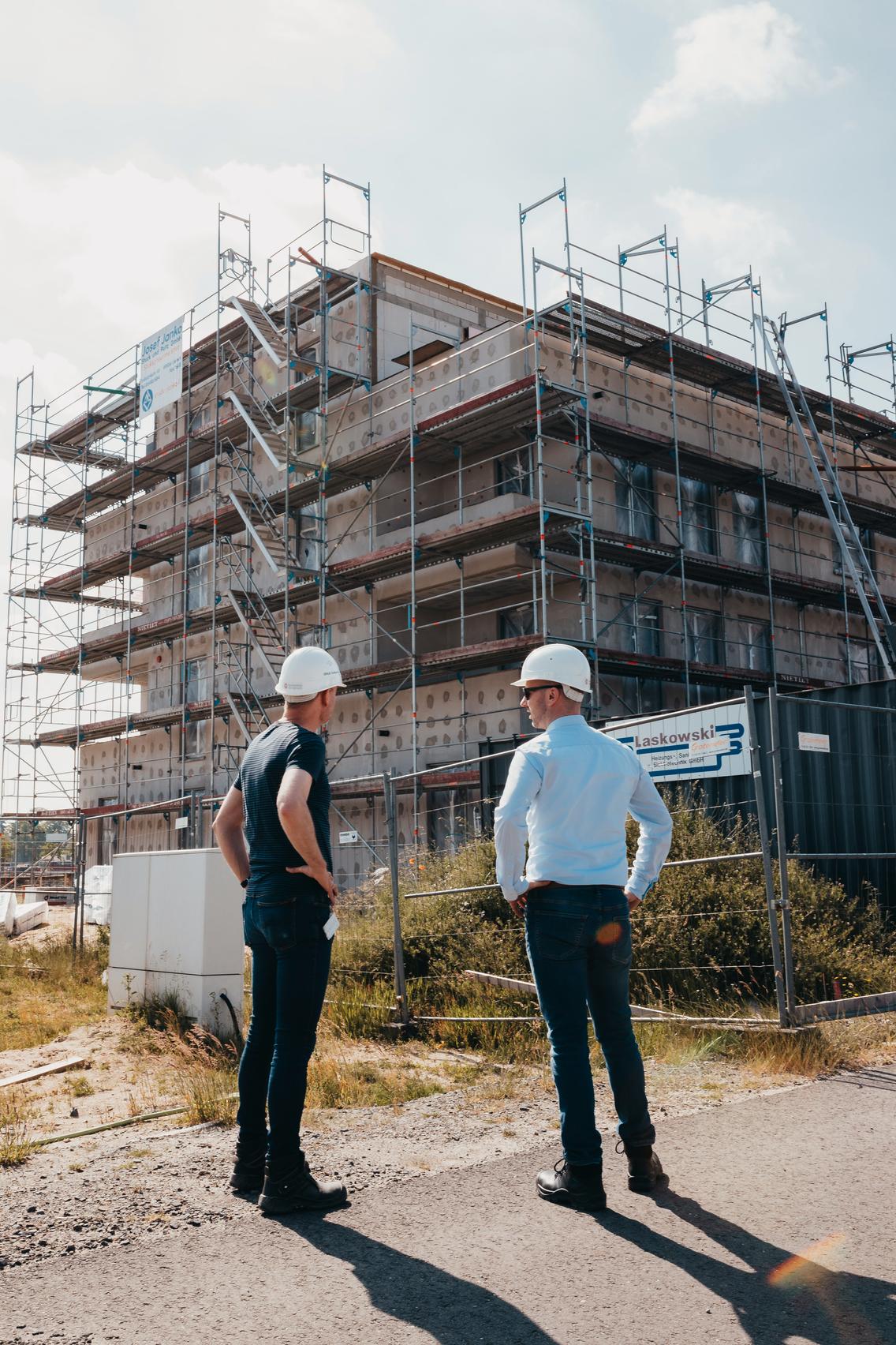 Zwei Kollegen unterhalten sich vor einem Bauprojekt