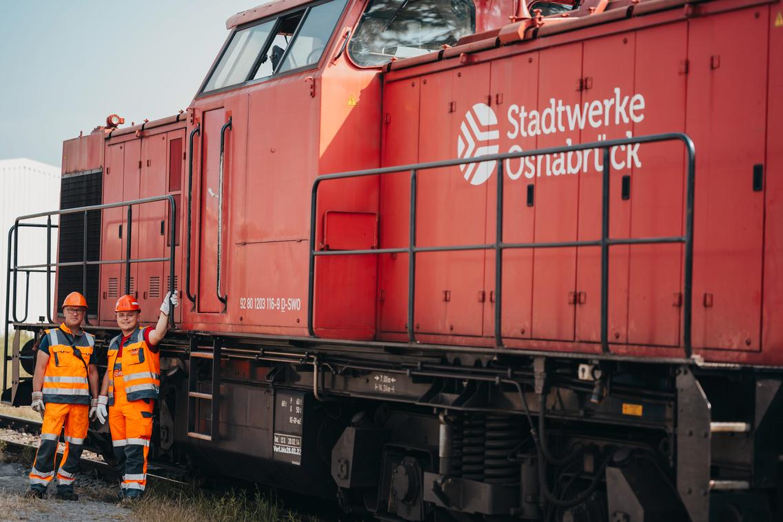 Zwei Männer stehen wir vor der Lok der EHB im Hafen