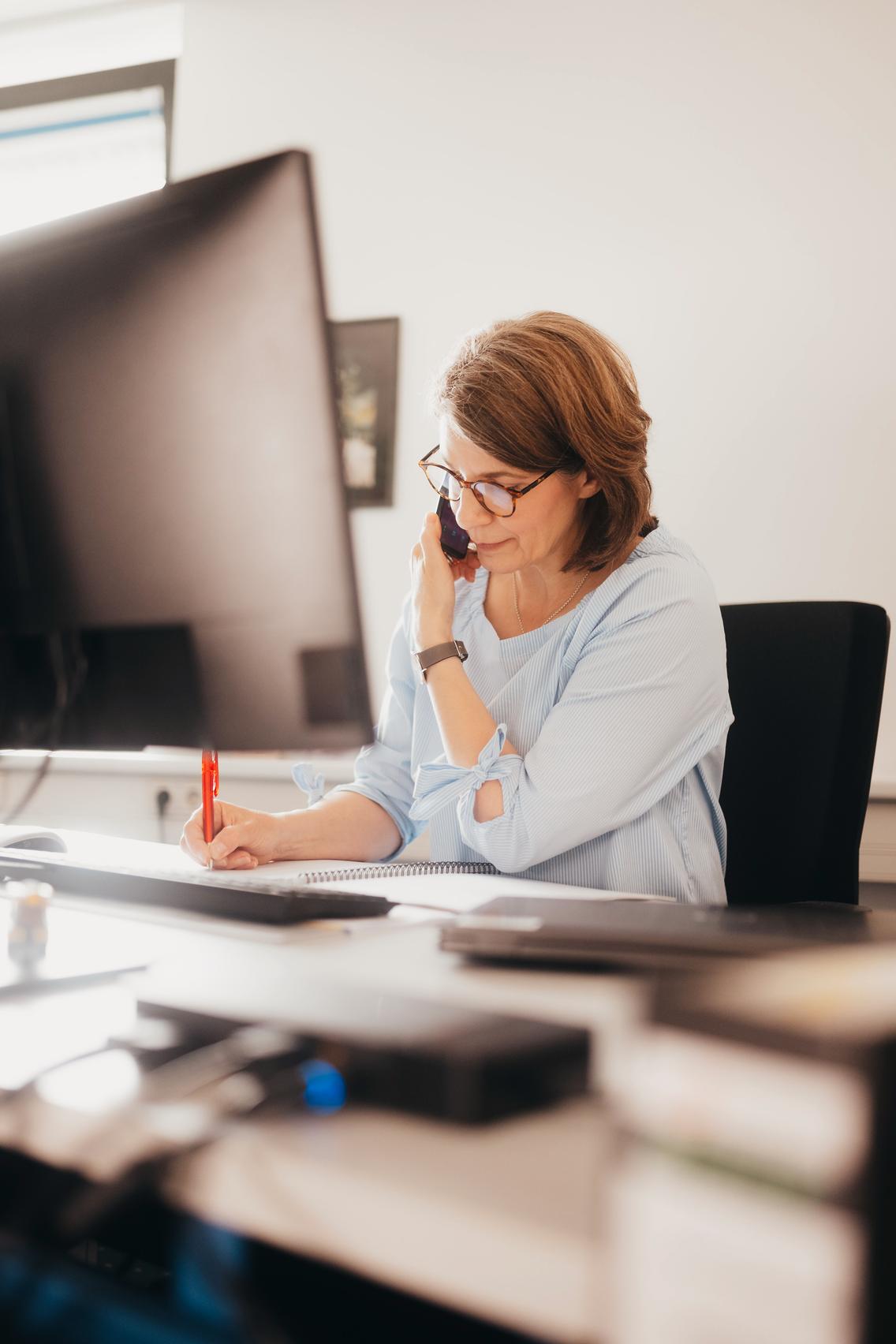 Frau telefoniert am Schreibtisch