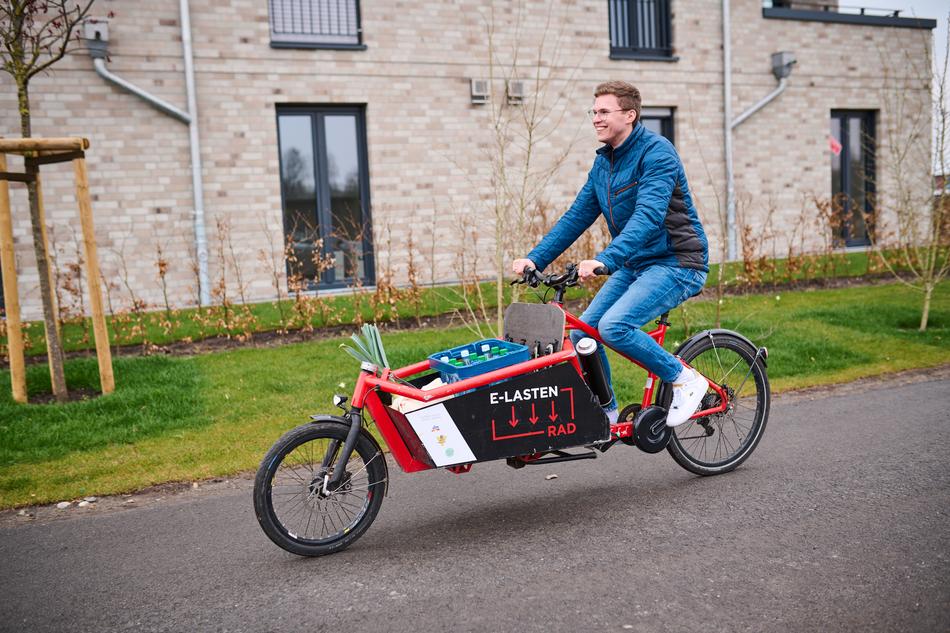 Junger Mann fährt auf einem Lastenrad nach Hause