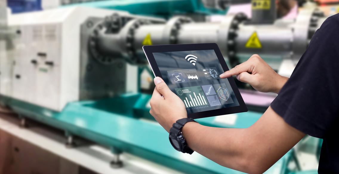 Mann mit Tablet an einer Maschine