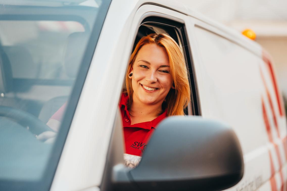 Frau sitzt lachend im Techniker-Auto