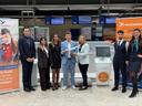 Gruppe von acht Personen am Check-in-Bereich des Albrecht Dürer Airport Nürnberg vor Self-Bag-Drop-Automaten; zwei Personen in der Mitte halten gemeinsam ein Modellflugzeug, flankiert von Werbeaufstellern der Fluggesellschaft Freebird und Monitoren mit Schalteranzeigen.