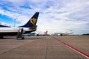 Flughafenvorfeld mit mehreren geparkten Flugzeugen. Im Vordergrund steht ein Ryanair-Flugzeug mit blau-gelbem Heck und Harfenlogo, eine mobile Treppe ist am hinteren Eingang angebracht. Im Hintergrund sind Maschinen von Turkish Airlines und Marabu zu sehen. Der Himmel ist teils bewölkt mit blauen Abschnitten, rote Linien markieren Bereiche auf dem Rollfeld.