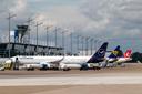 Flugzeuge von Lufthansa, Ryanair und Turkish Airlines stehen auf dem Vorfeld vor dem Terminal mit Kontrollturm des Flughafens Nürnberg unter bewölktem Himmel.