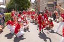 Eine Samba-Percussion Band in rot-weißen Uniformen in einer Straße bei sonnigem Wetter