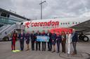 Gruppe von Personen steht vor einem Corendon Airlines Flugzeug am Flughafen Nürnberg und hält ein großes Schild mit Werbeaufdruck. Links ist eine Person im Taucheranzug zu sehen, rechts mehrere Personen in Business- und Flugbegleiter-Uniformen.