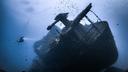 Ein Taucher vor einem versunkenen Wrack eines Schiffes im Meer