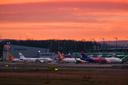 Mehrere Flugzeuge verschiedener Airlines vor dem Terminal des Airport Nürnberg im Morgengrauen, im Hintergrund orangener Himmel.