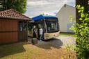 Bus steht an einer Haltestelle, Menschen steigen ein.
