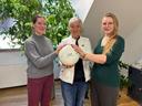 Zwei junge Frauen stehen rechts und links neben der Bürgermeisterin. Die drei haben ihre Hände auf einen Ball gelegt, den die Bürgermeisterin hält.
