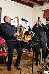  Im Vordergrund ein Saxophonist und ein Klarinettist beim leidenschaftlichen Spiel, im Hintergrund ein Gitarrist
