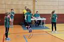 Ein Mädchen springt mit einem Sprungseil. In der Turnhalle stehen weitere Kinder und schauen zu.