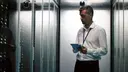 IT-Infrastruktur-Spezialist überwacht hochverfügbare Server-Racks in einem modernen Rechenzentrum per Tablet.